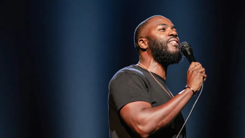 Mo Gilligan performing on stage with blue lighting